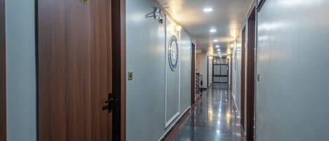 A hallway with wooden doors, a number plate, a decorative plate, and a ceiling light fixture.
