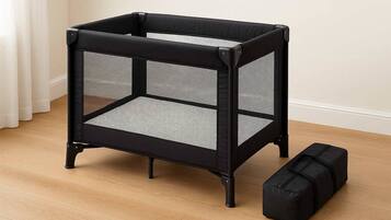 Un berceau en métal noir avec un motif en treillis, un banc de rangement assorti et un plancher en bois.