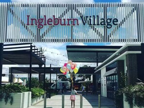 Entrada de um edifício moderno com uma placa indicando 'Ingleburn Village'.
