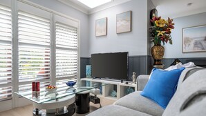 A modern living room with a glass coffee table, grey sofa, and a flat-screen TV. - Peaceful 2BR Villa Retreat (Ingleburn)