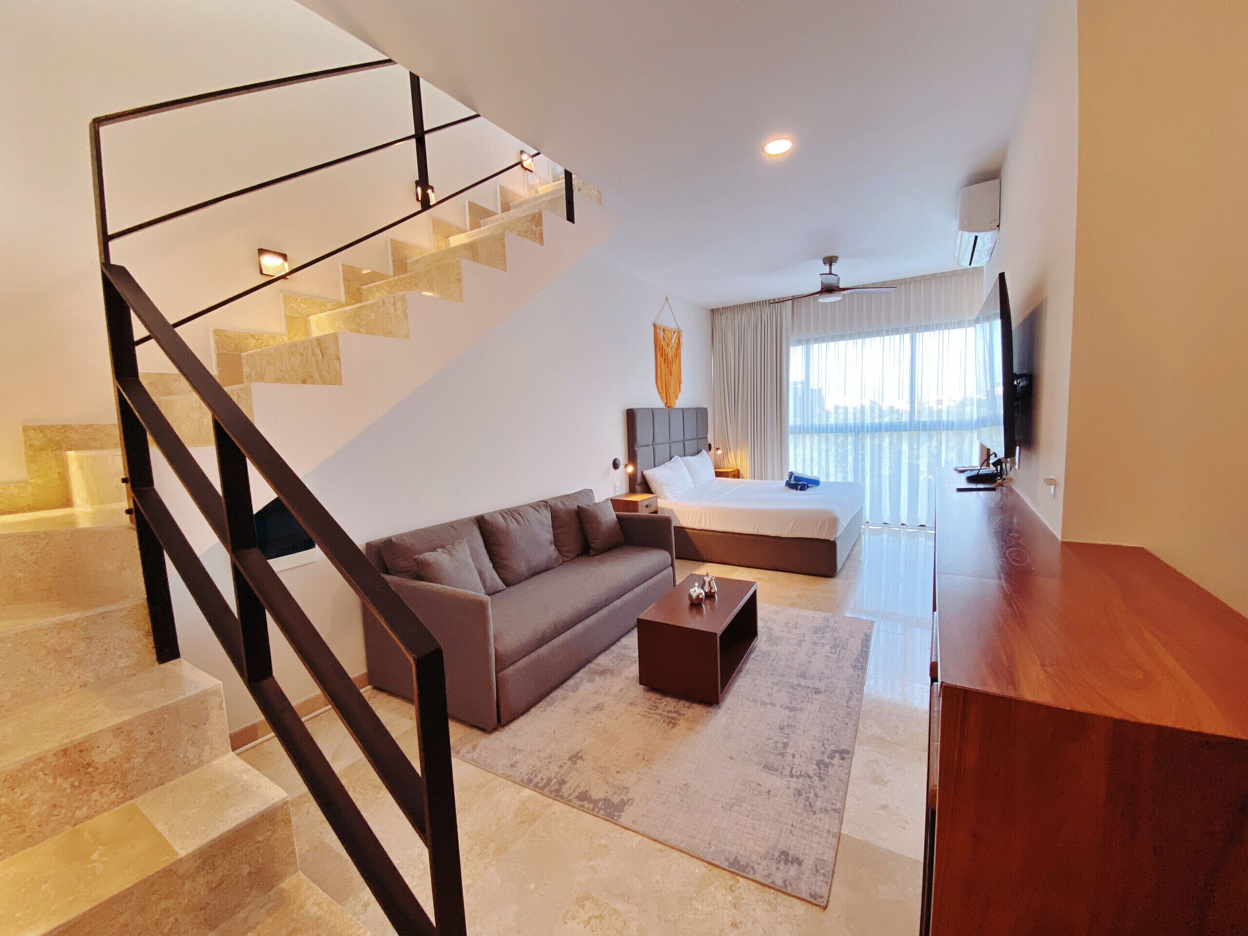 Un salon moderne avec un escalier, un canapé, une table basse et un lit.