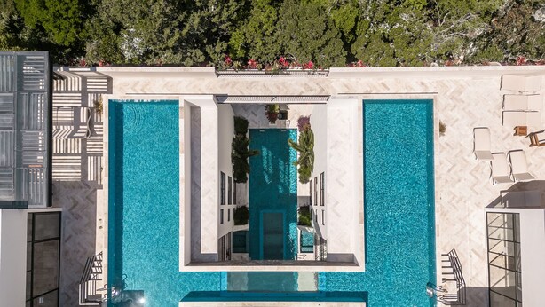 Ein Poolbereich im modernen Stil mit geometrischem Design, inklusive einer zentralen Wasserspiels und umgebenden Sitzbereichen.