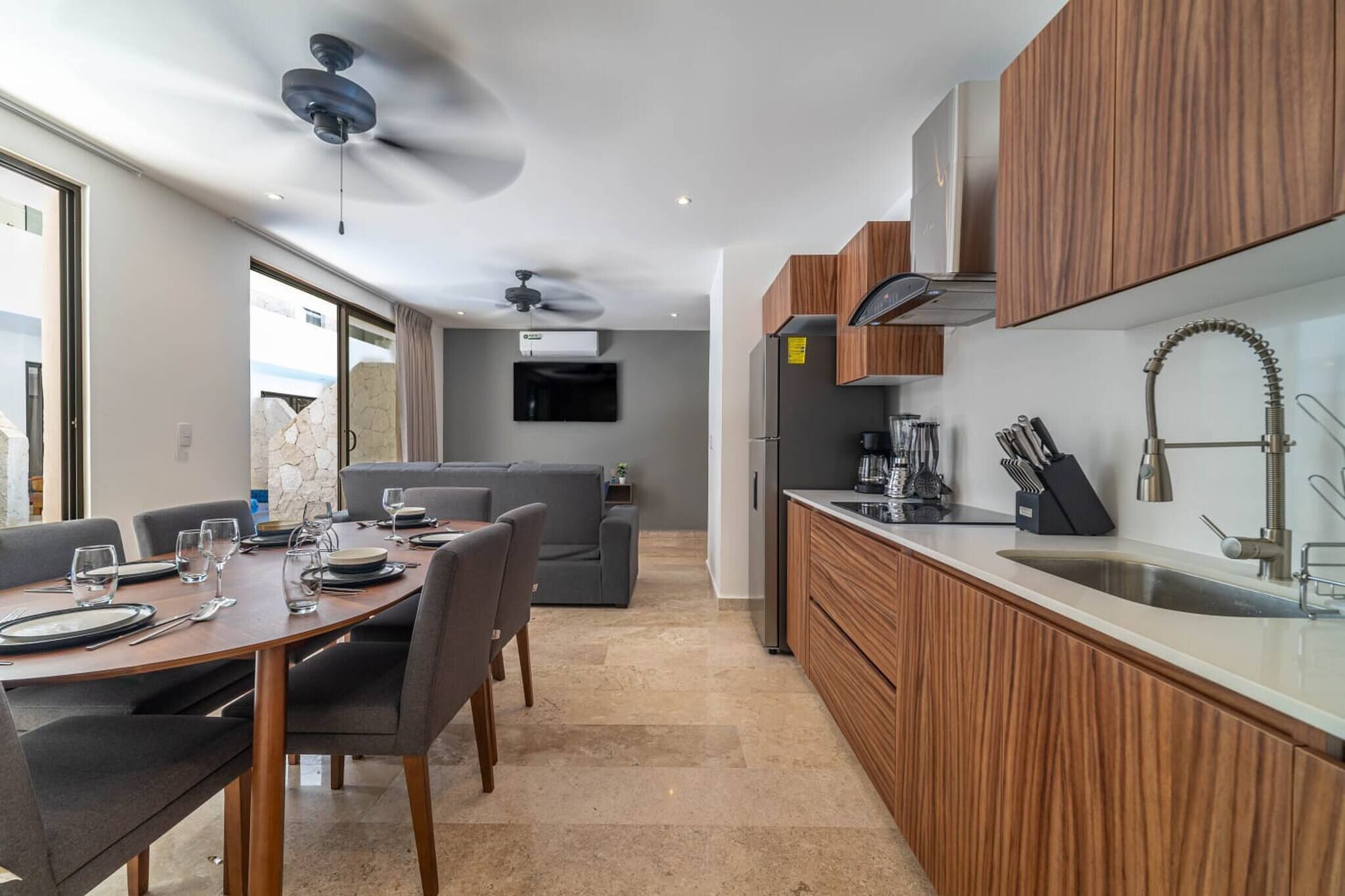 A modern kitchen with wooden cabinets, a built-in sink, and a dining area with a table set for four.