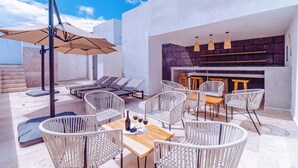Une terrasse extérieure avec des fauteuils de jardin, une table avec des verres à vin et une cheminée en pierre.