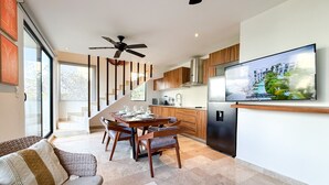 Een moderne keuken met een inbouwoven, een eethoek met een houten tafel en stoelen, en een grote flatscreen televisie aan de muur.