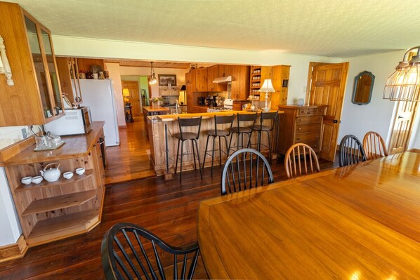 A spacious kitchen with wooden cabinets, a central island with bar stools, and a dining table with chairs.