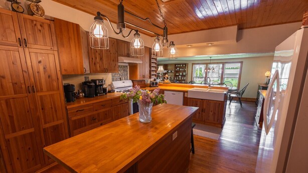 A spacious kitchen with wooden cabinets, a central island, and pendant lighting. - Peaceful Pepin Farmhouse Getaway (Pepin)