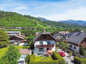 Un quartier résidentiel avec des maisons, une voiture rouge et une montagne en arrière-plan.
