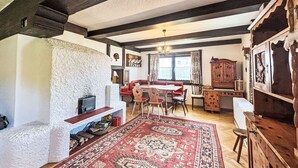 Un interior rústico con chimenea de piedra, muebles de madera y un gran tapiz rojo.