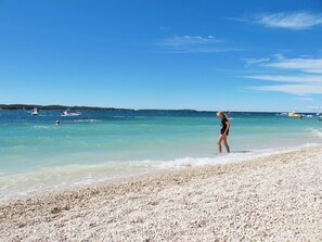 A beach with clear water and a pebbly shore.