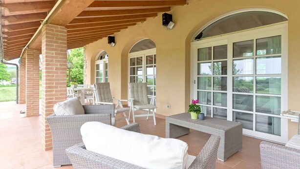A covered patio area with wicker furniture, large windows, and a brick wall. - Wonderful private villa for 6 guests with A/C, WIFI, TV, patio, pets allowed and panoramic view (Roccastrada)