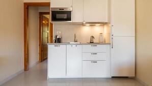 Une cuisine moderne avec des meubles blancs, un four à micro-ondes, une machine à café et un réfrigérateur.