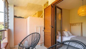 Un balcon avec deux chaises en fil de fer noir, une petite table ronde et un vase décoratif blanc.