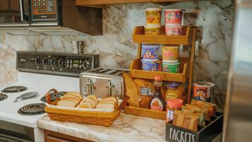 A kitchen with a marble countertop, a toaster, a bread basket, and a display of breakfast items including cereals and spreads.