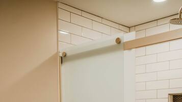 Une salle de bain avec des toilettes, une douche en verre et des murs recouverts de carrelage blanc.