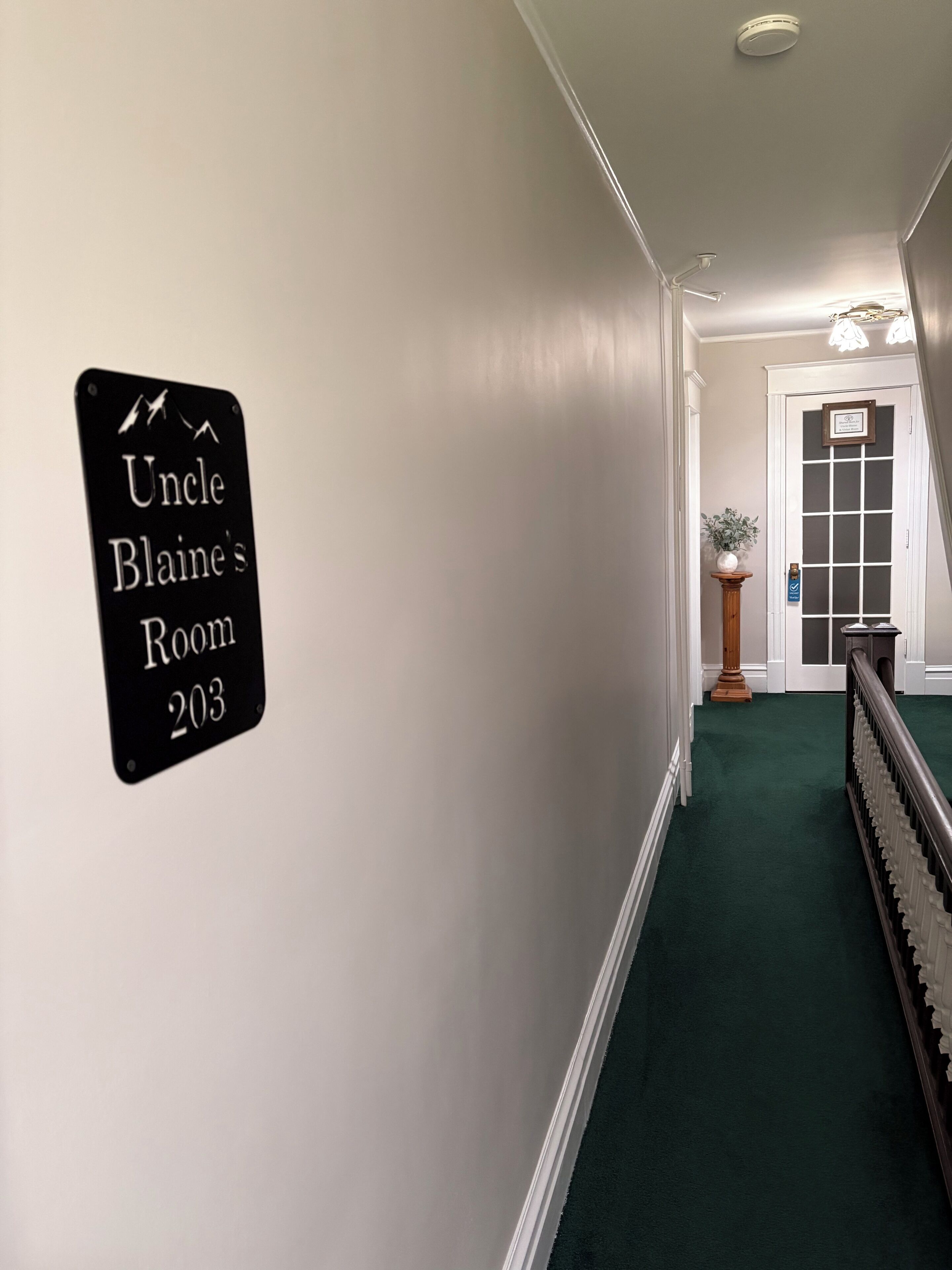 A hallway with a sign reading 'Uncle Blaine's Room 203' on the wall.