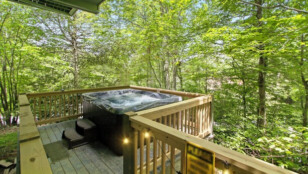 Un bain à remous sur une terrasse en bois, entouré d’une végétation luxuriante.