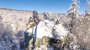 Une maison recouverte de neige, avec un porche et un ciel bleu dégagé.