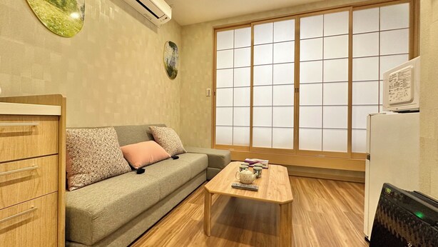 Habitación con sofá, mesa de madera, refrigerador y puerta corrediza de vidrio con vista.