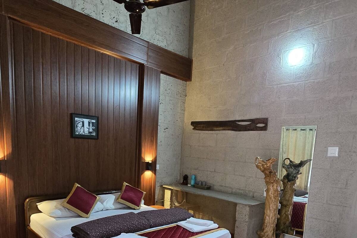 A bedroom with a wooden bed, a ceiling fan, a large mirror, and a rustic decor piece.