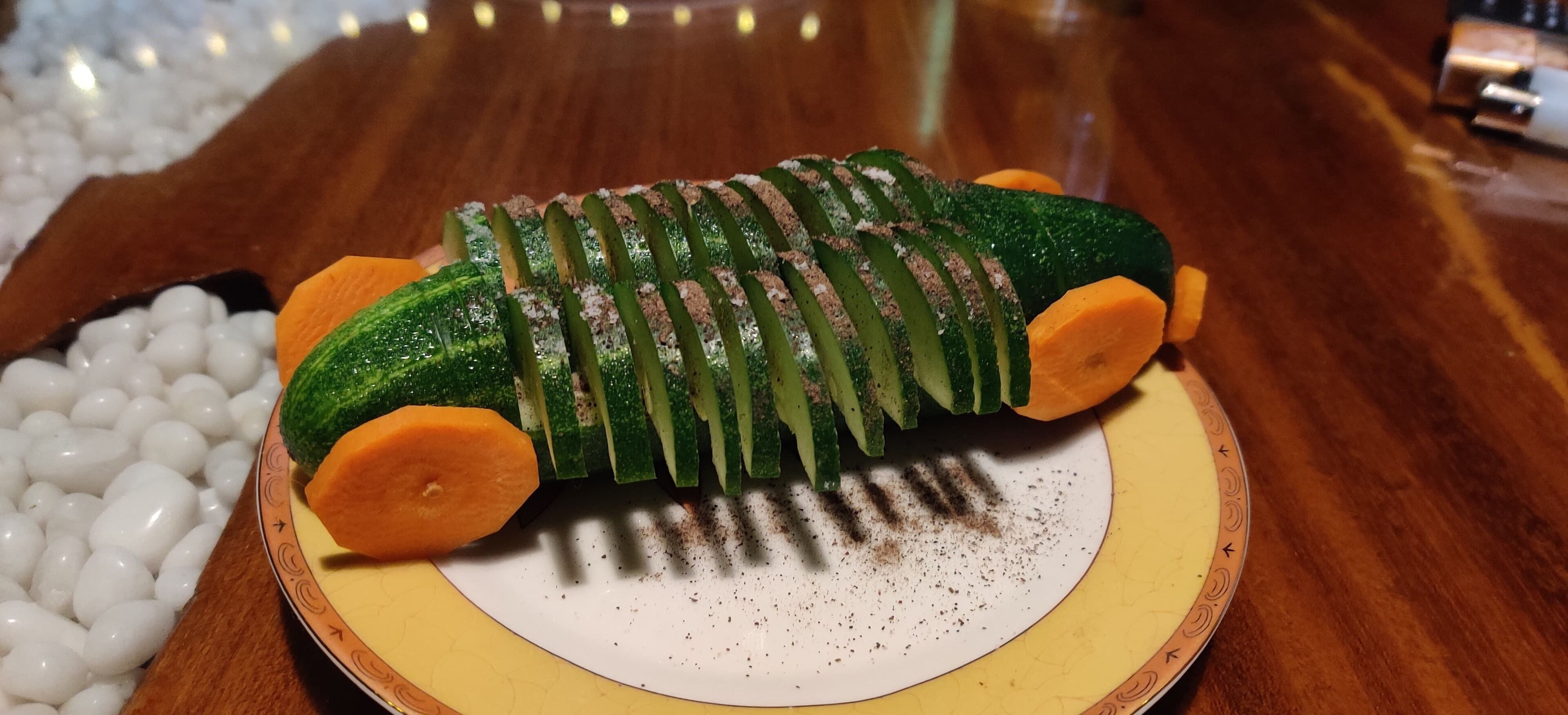 A plate with sliced vegetables and a decorative item resembling a caterpillar.
