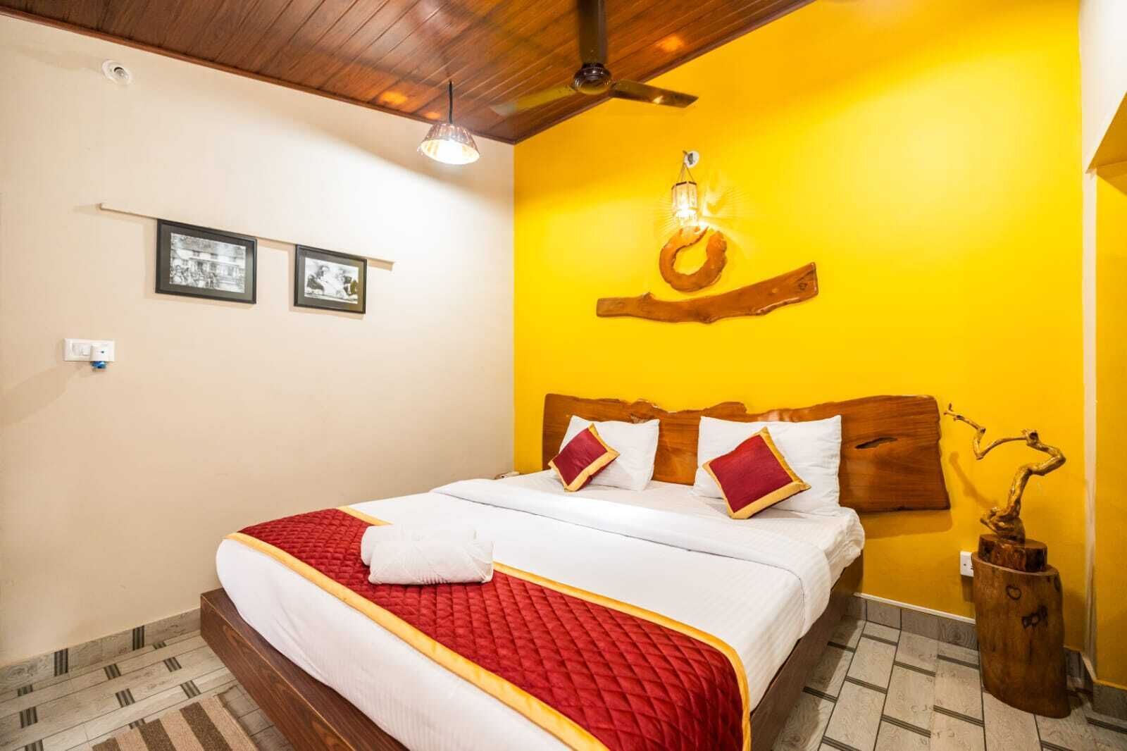 Una habitación de hotel con una cama, un ventilador de techo y un cabecero de madera.
