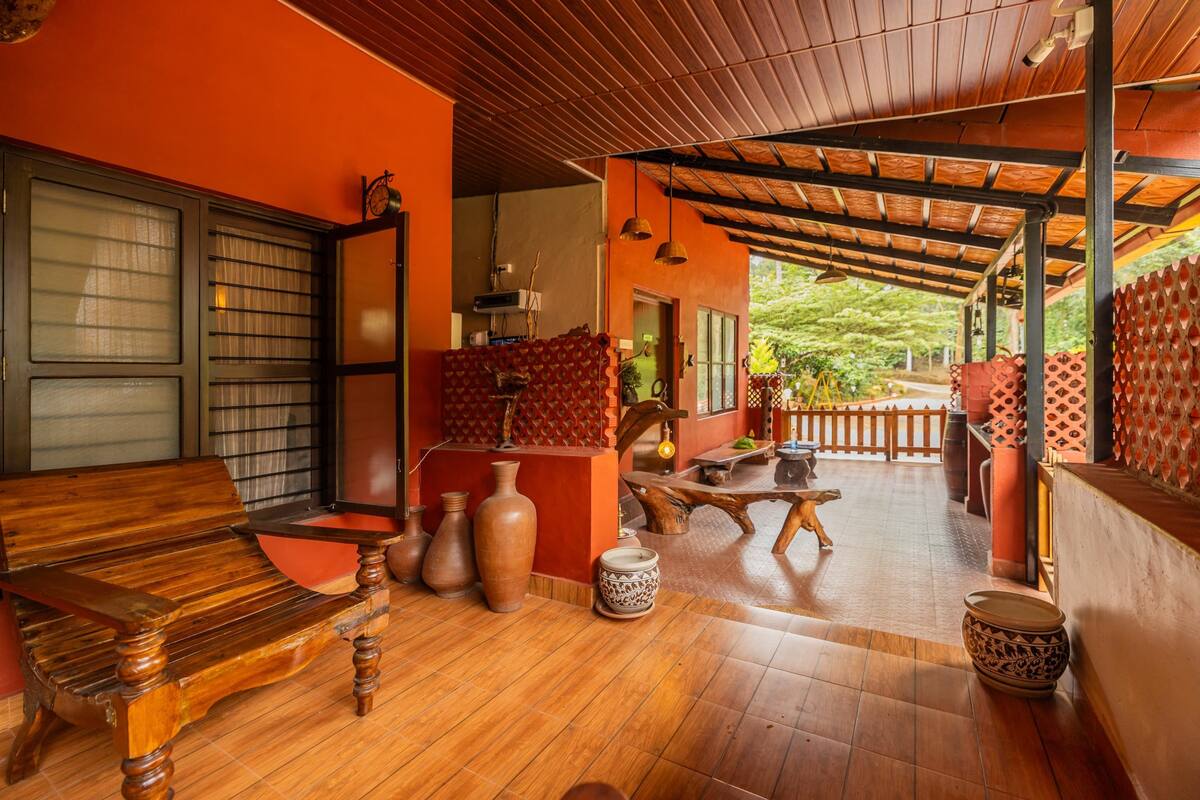 A wooden bench, a table, and several pottery items in a room with orange walls and a wooden ceiling.