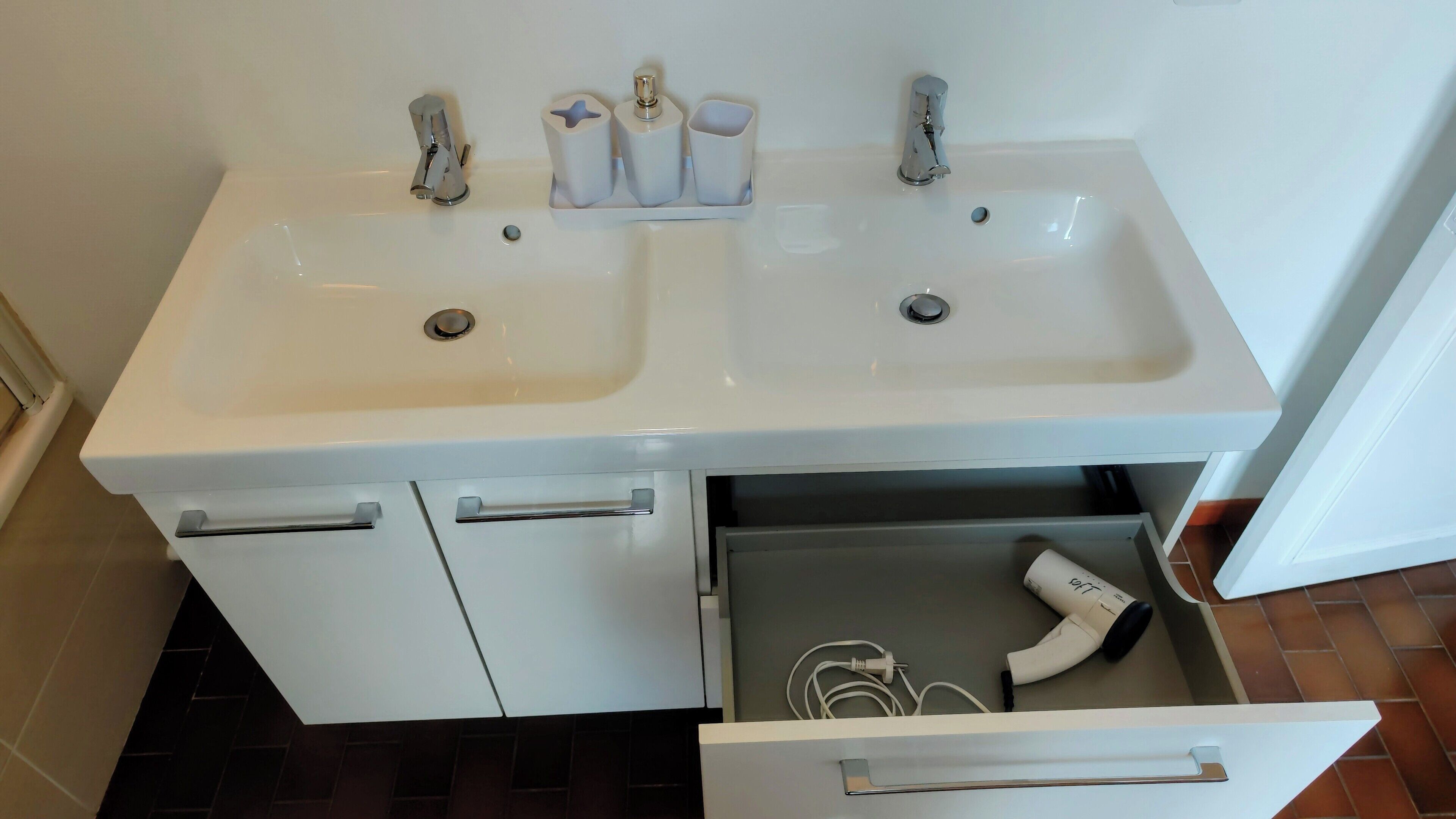 A bathroom with two sinks, a hairdryer, and a towel rack.