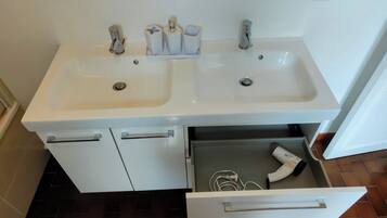 A bathroom with two sinks, a hairdryer, and a towel rack.