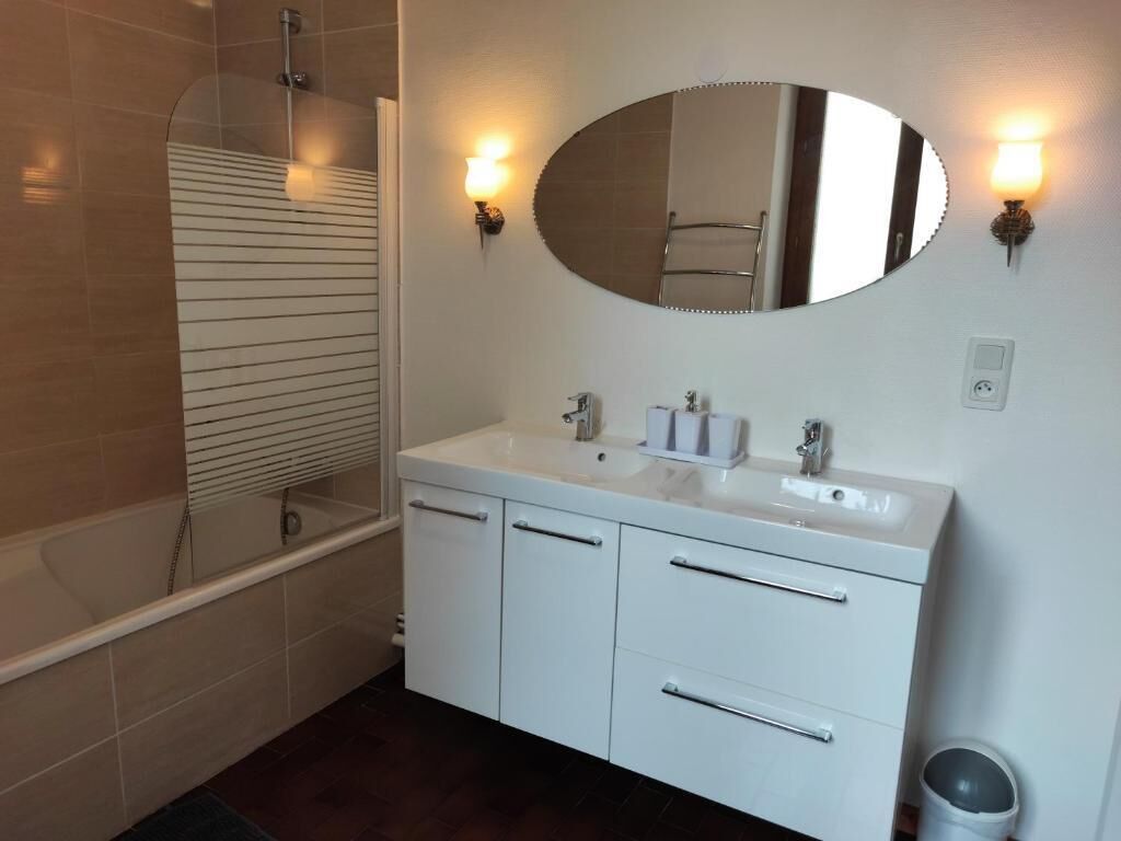 Un bagno con una vasca, un lavandino con uno specchio sopra e due luci a parete.