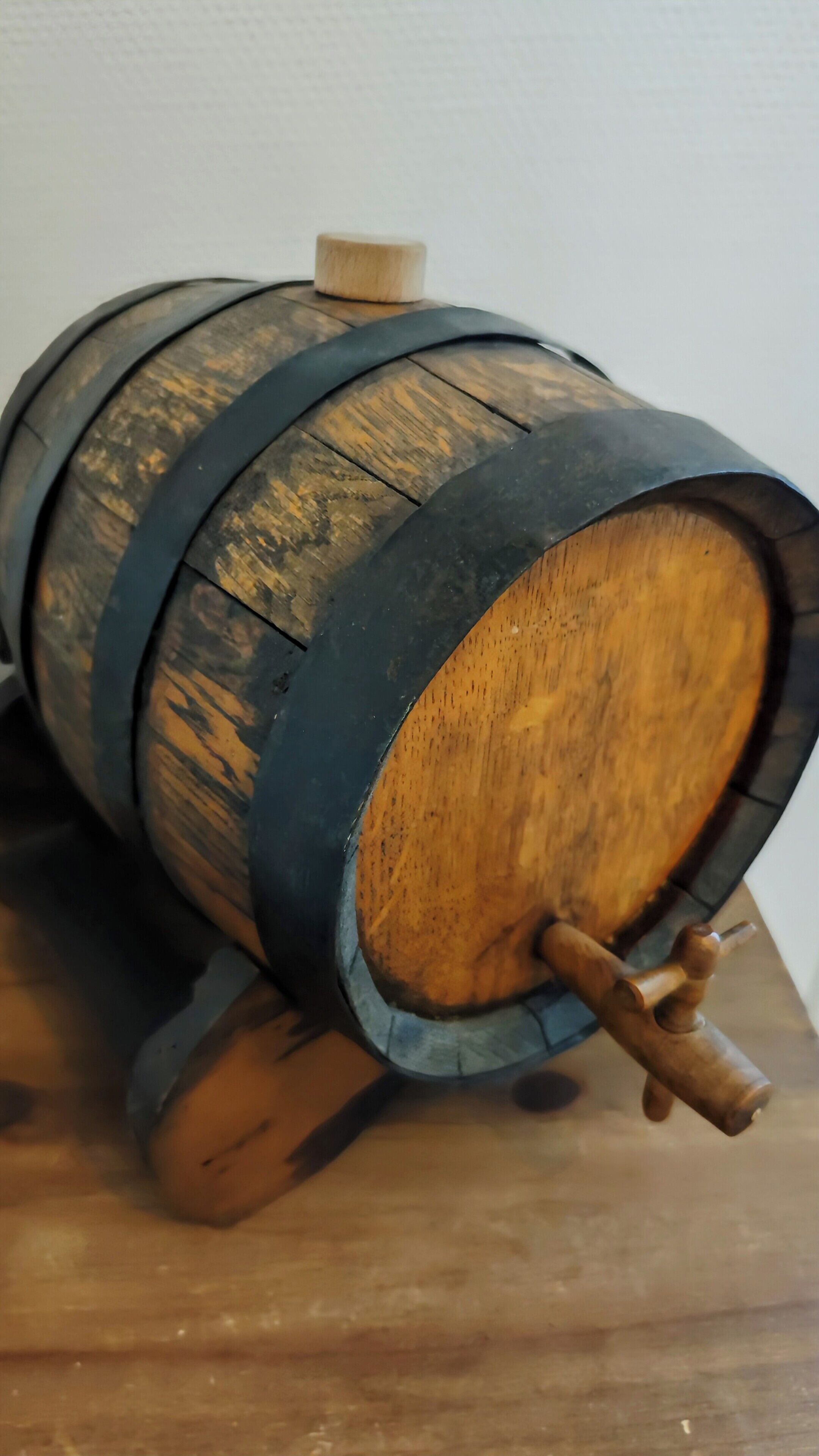 Un tonneau en bois, renforcé par des cercles métalliques et doté d’une anse en bois.