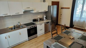 Una cocina moderna con armarios blancos, electrodomésticos de acero inoxidable, lavavajillas y refrigerador.