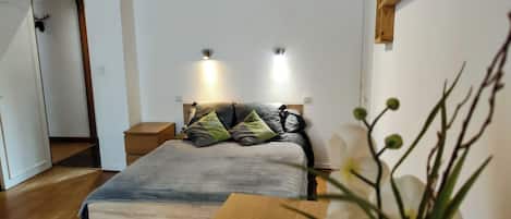 Un dormitorio con cama, mesitas de noche, una mesita auxiliar de madera, un estante montado en la pared y una puerta decorada con una cabeza de ciervo.
