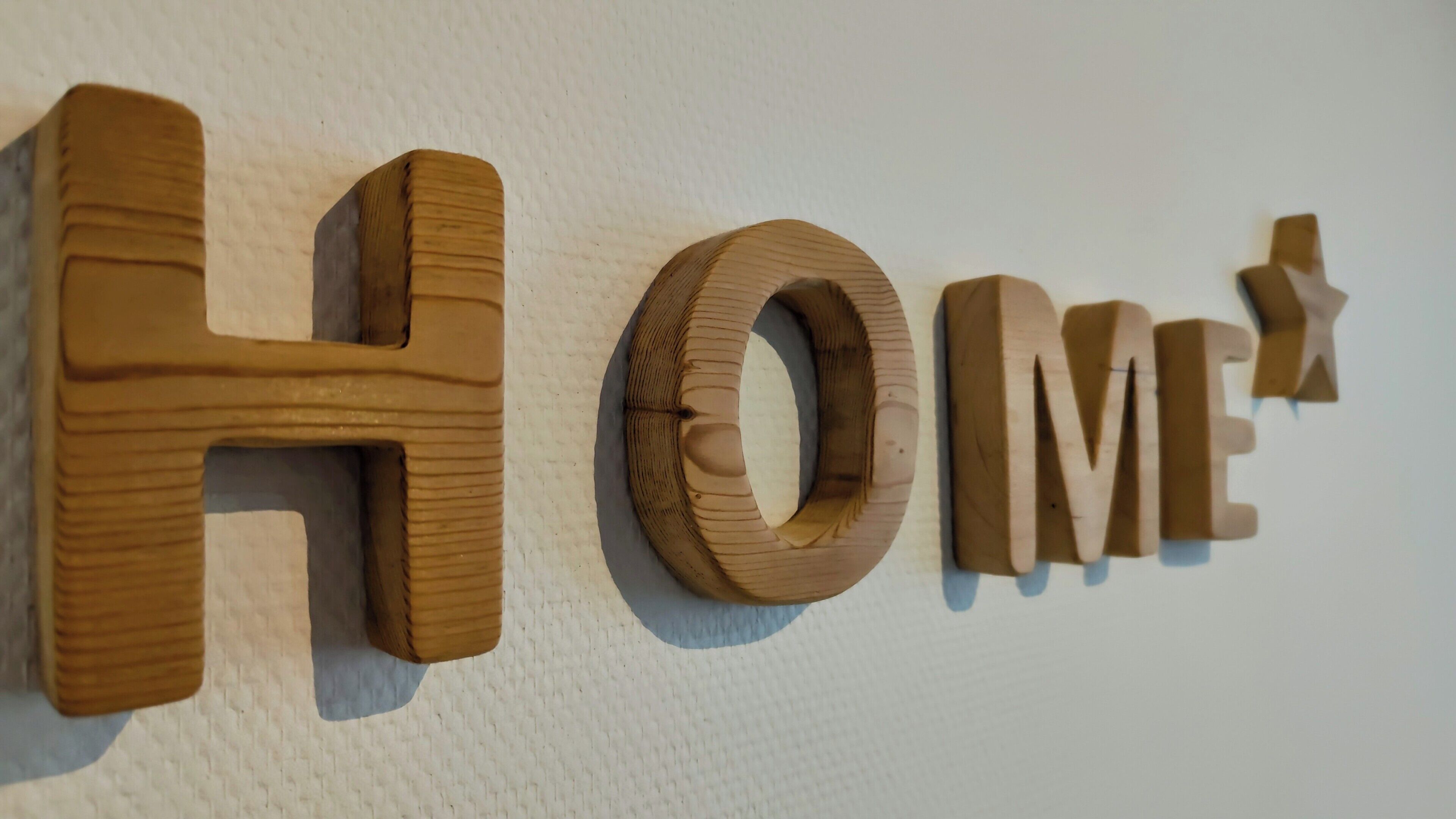 Wooden letters spelling "HOME" on a textured wall.