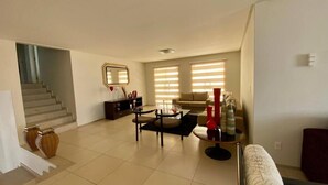 A spacious living room with a staircase, a round coffee table, and a sofa. - Casa com Piscina - Quartos Privativos (Sao Raimundo Nonato)