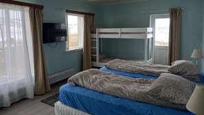 A bedroom with two bunk beds, a television, and a window with curtains.