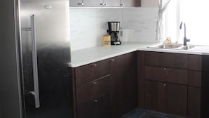 A kitchen with dark wooden cabinets, a stainless steel refrigerator, a coffee maker, and a sink with a faucet.
