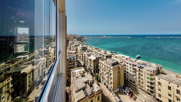 A high-rise building with a view of a coastal cityscape, including a marina and densely packed buildings.