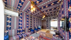 A room with patterned walls and a striped carpet, a sofa, a table, and a hanging light fixture.