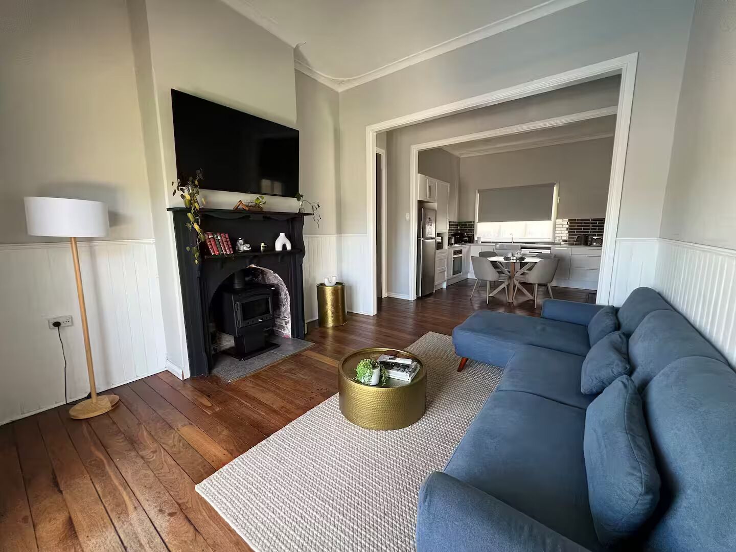 A living room with a blue sofa, a fireplace, and a kitchen in the background.