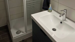 Un bagno moderno con doccia vetrata, un lavandino bianco con specchio e un porta asciugamani.