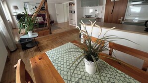 Una cucina accogliente con travi in legno, un'area pranzo con tavolo e sedie, e una pianta in vaso.