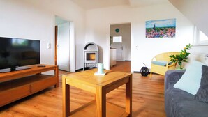 A living room with a TV, wooden furniture, a fireplace, and a painting on the wall. - NEW Apartment Blumenstraße in Korbach (Korbach)