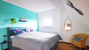 A bedroom with a bed, a chair, a window, and a wall decoration. - NEW Apartment Blumenstraße in Korbach (Korbach)