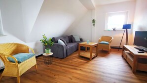 A cozy living room with a sofa, two chairs, a coffee table, a TV stand, and a potted plant. - NEW Apartment Blumenstraße in Korbach (Korbach)