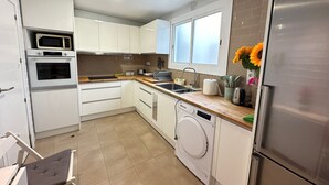 A modern kitchen with white cabinets, a built-in microwave, a dishwasher, and a stainless steel refrigerator. - Rooms Borrell (Barcelona)