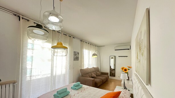 A modern bedroom with a bed, a chair, a sofa, and a desk. - Rooms Borrell (Barcelona)