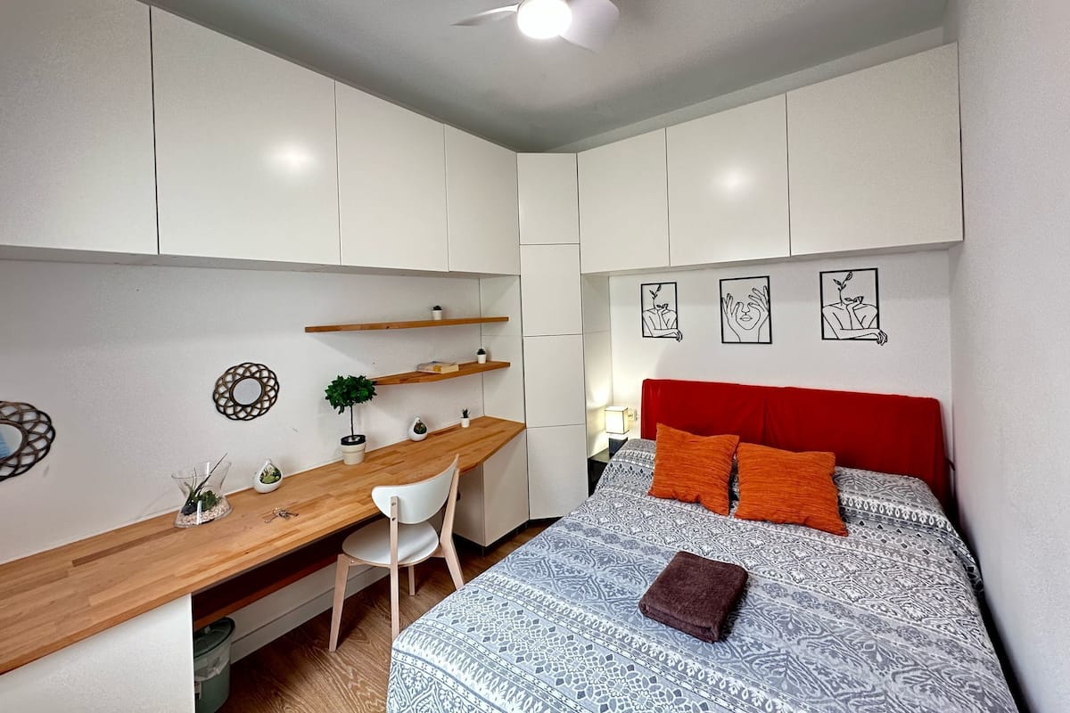 Un dormitorio pequeño con una cama, un escritorio y una silla.