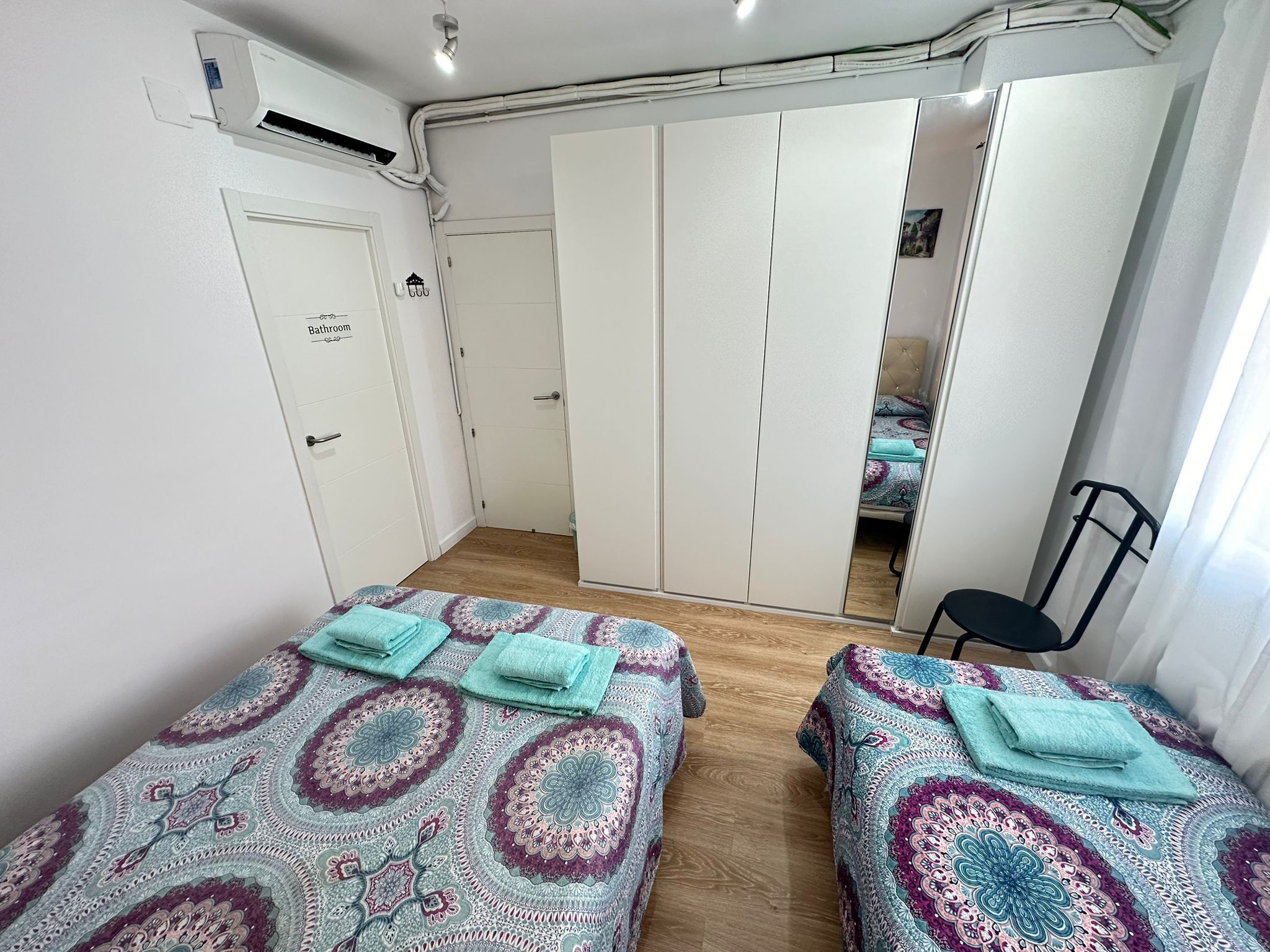 A bedroom with two beds, a wardrobe, and a bathroom.