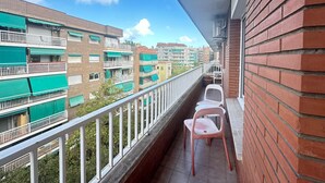 A balcony with a view of neighboring buildings, a white railing, and a pink chair. - Rooms Borrell (Barcelona)